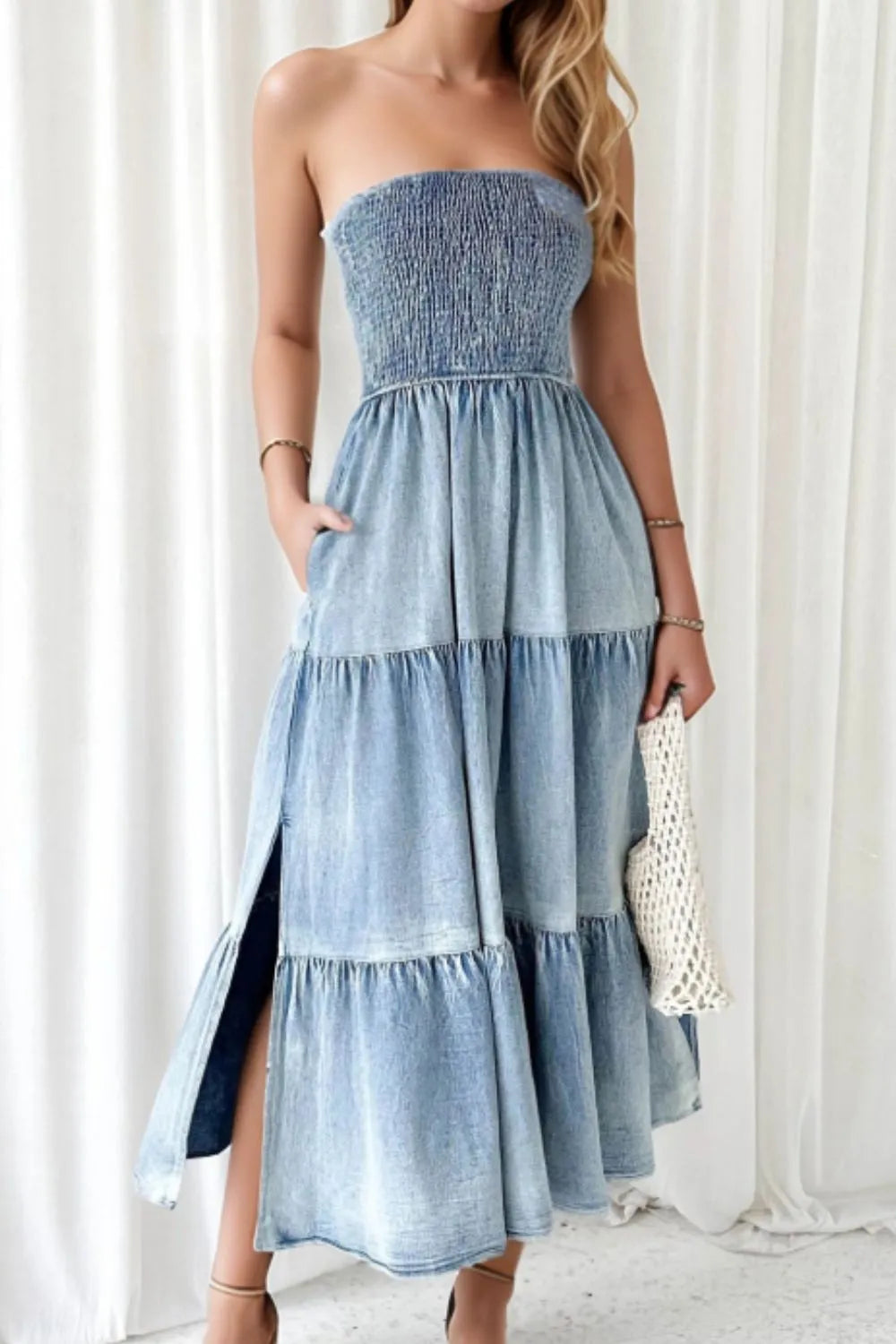 Light blue smocked tube denim dress with slit and tiered design, featuring trendy details perfect for casual or stylish occasions.