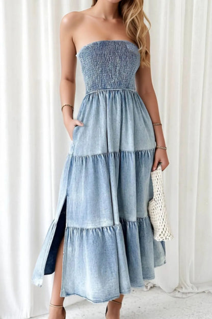 Light blue smocked tube denim dress with slit and tiered design, featuring trendy details perfect for casual or stylish occasions.