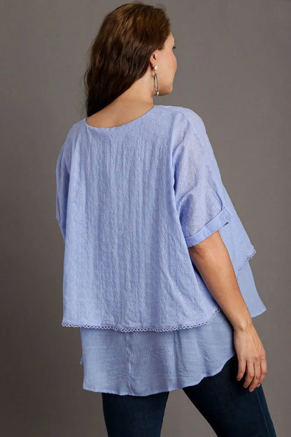 Light blue Plus Size Umgee eyelet layered short sleeve blouse with feminine design and eyelet details, styled for a casual look.
