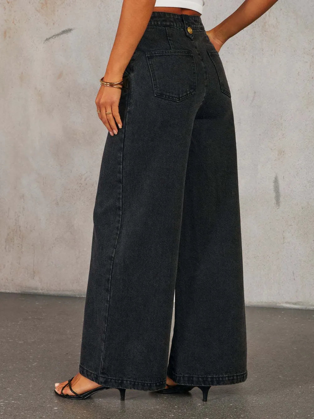 Light wash high-rise wide-leg jeans with button decor from Trendsi, featuring a relaxed fit and classic denim style.