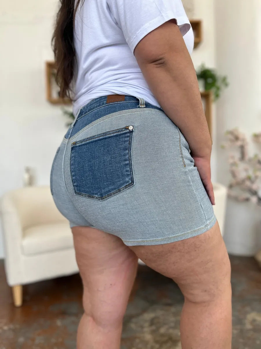 Color block denim shorts by Judy Blue featuring a full-size fit, displayed in a natural pose with vibrant blue, white, and black color blocks.