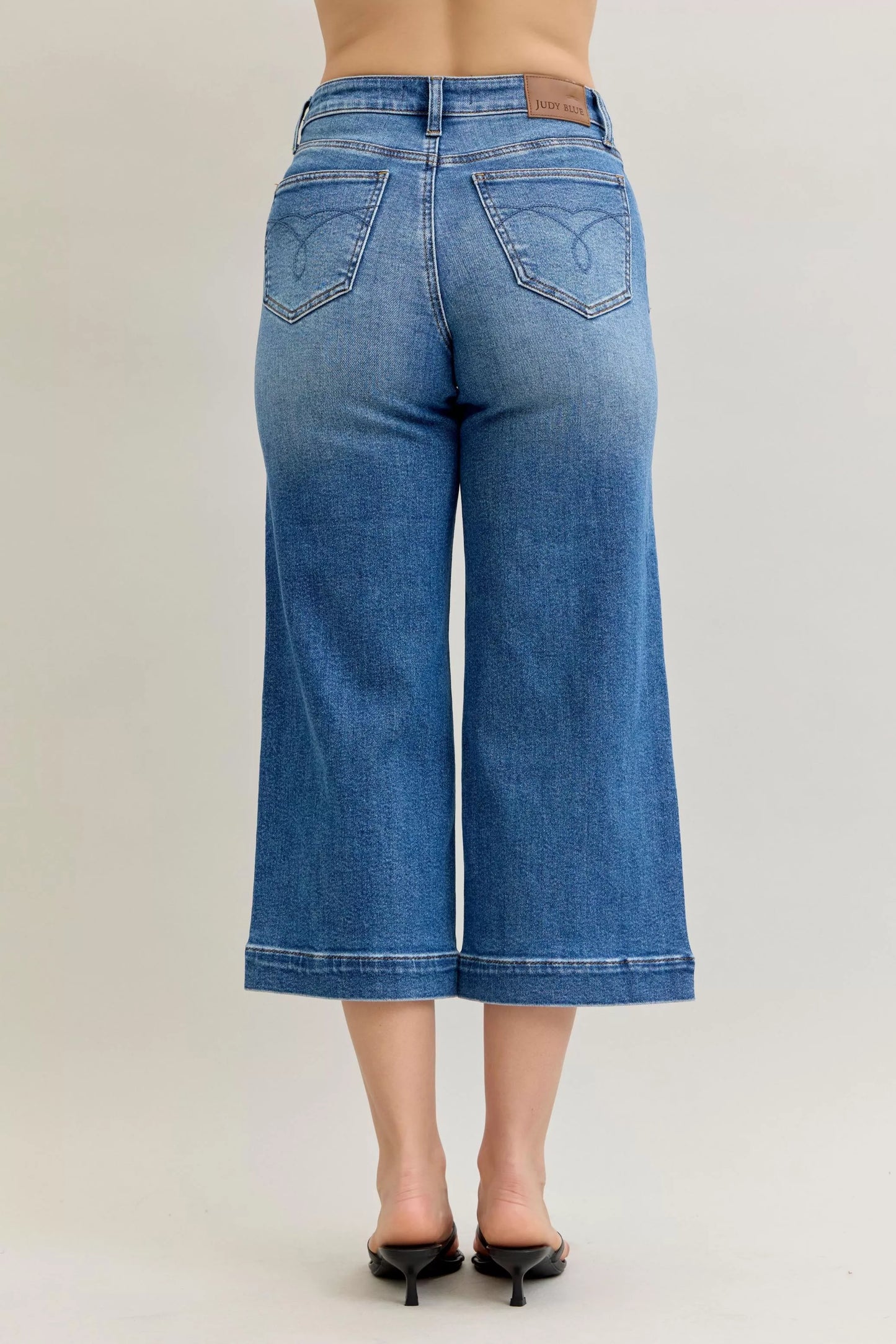 Pair of Judy Blue mid-rise crop wide-leg jeans from Trendsi, showing relaxed fit and classic denim style.