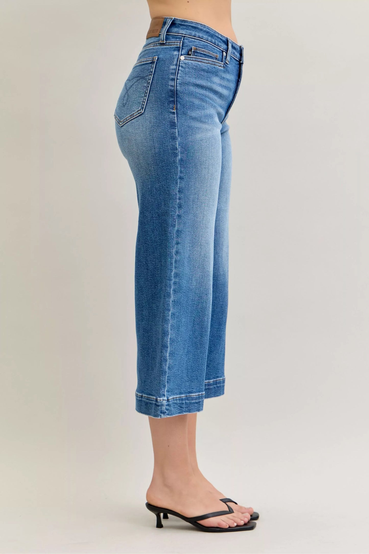 Light blue Judy Blue mid-rise crop wide-leg jeans with distressed details, styled on a hanger.