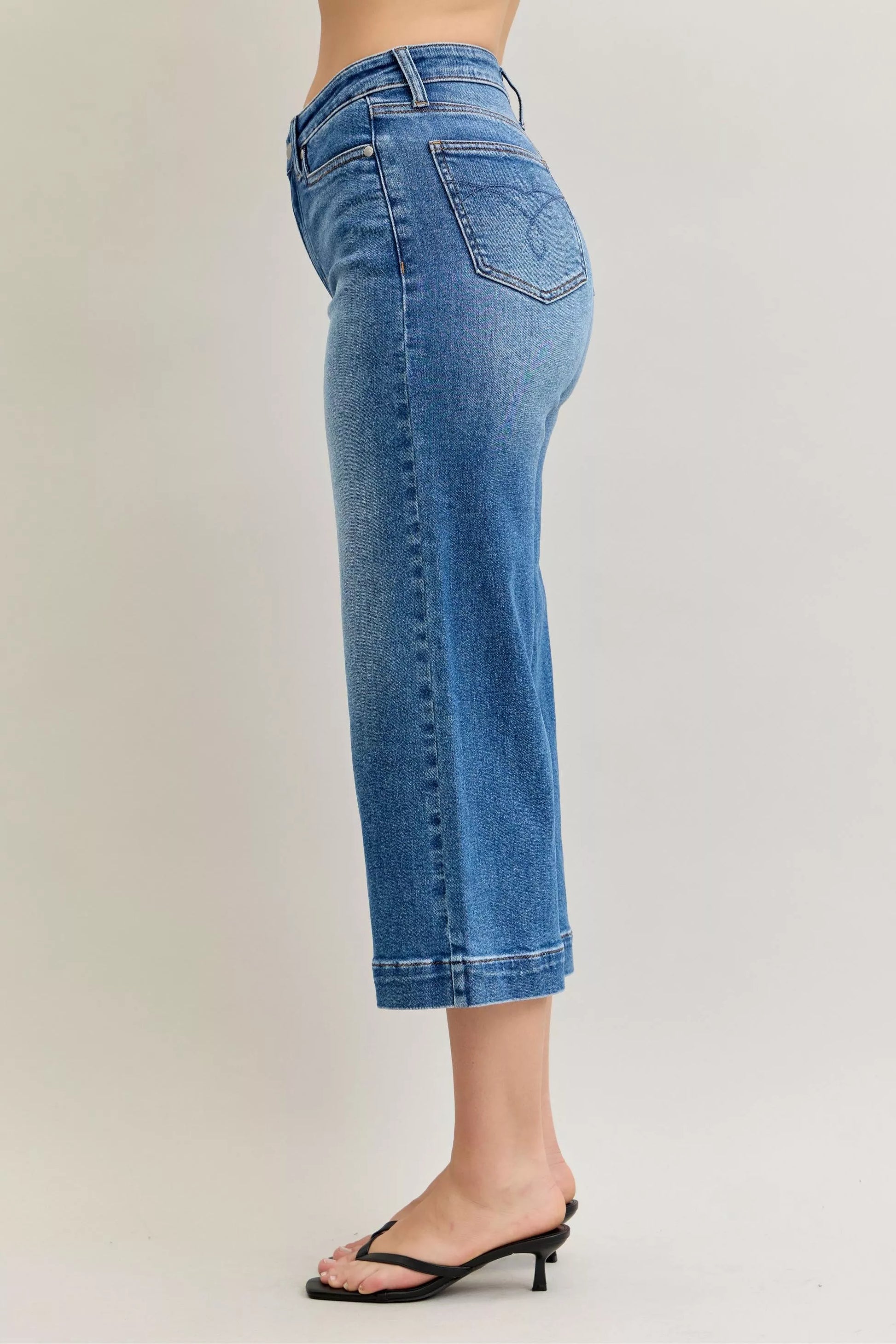 Light wash Judy Blue mid-rise crop wide-leg jeans with distressed details and frayed hems, styled on a model.