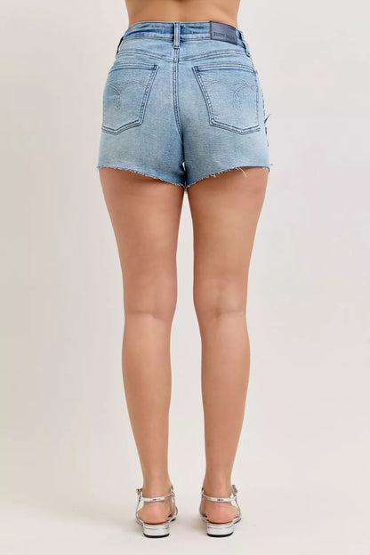 Judy Blue HW Rigid Magic Cut Off Denim Shorts with raw side seams, showcasing distressed denim and frayed edges.