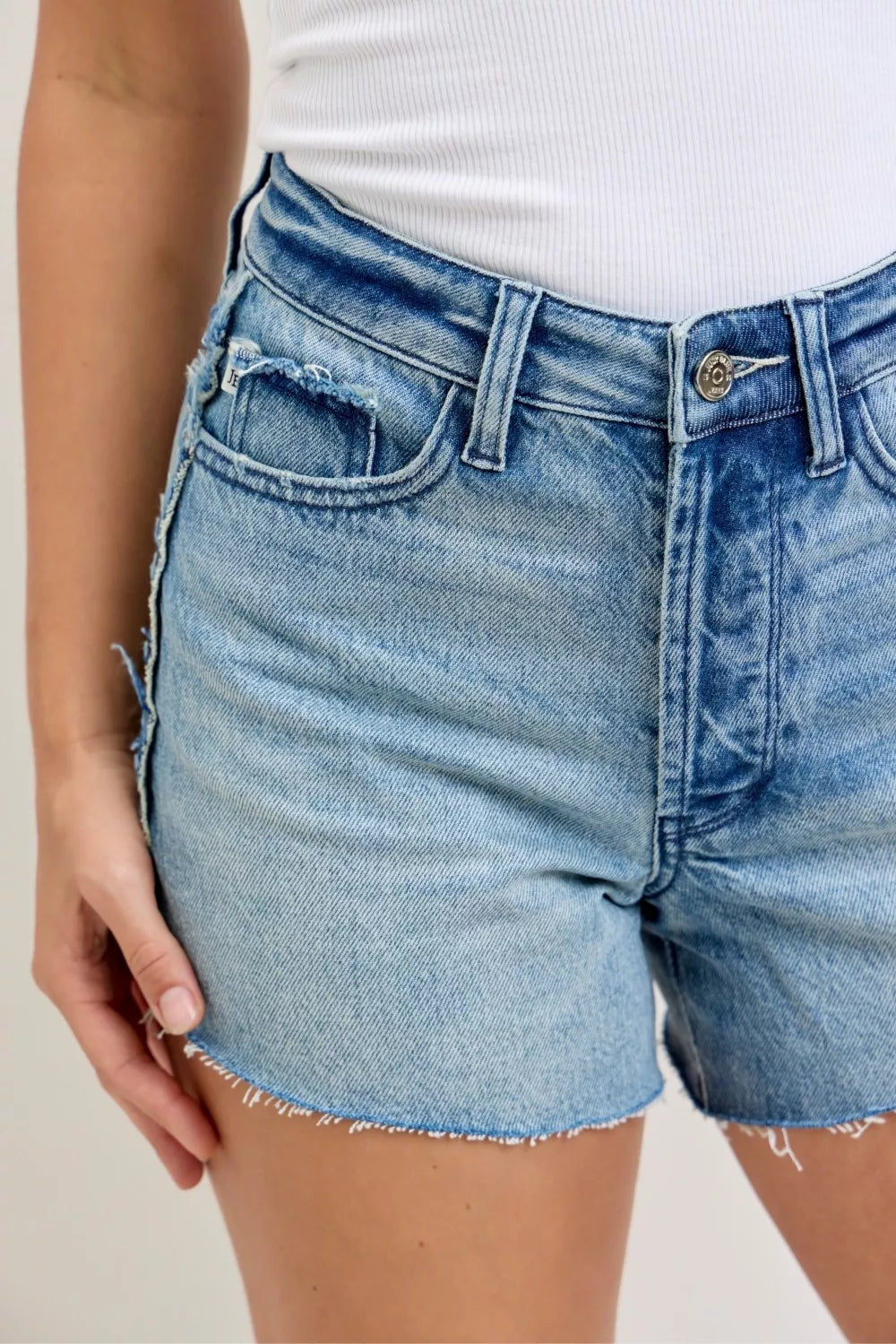 Judy Blue Rigid Magic Cut-Off Denim Shorts with raw side seams, featuring distressed hem and classic blue wash.