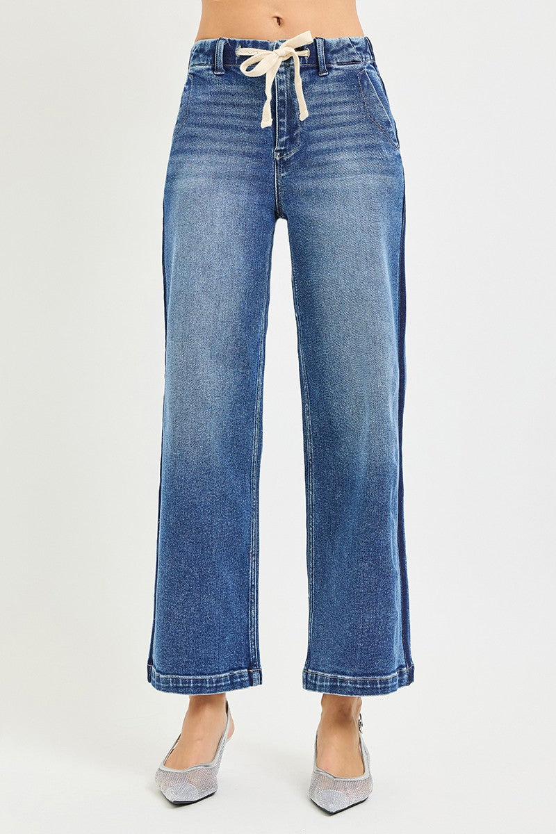 Risen high-rise cropped wide jeans with elastic band and distressed details, styled with a casual top and sneakers.