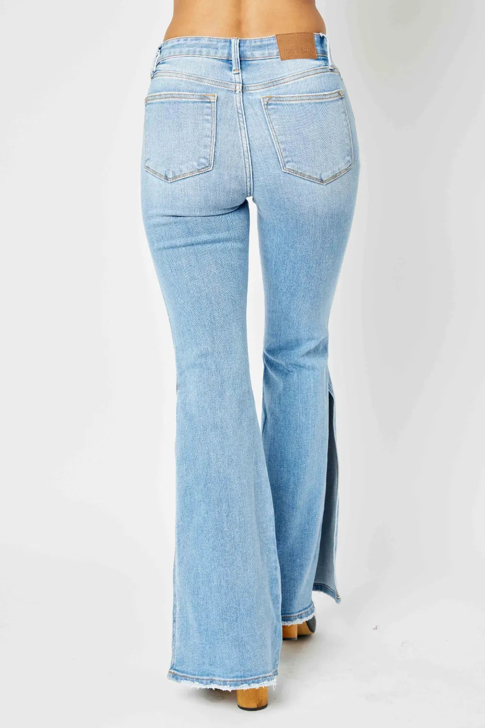 Judy Blue full size mid-rise flare jeans with raw hem and slit details, featuring a trendy distressed look and classic denim wash.