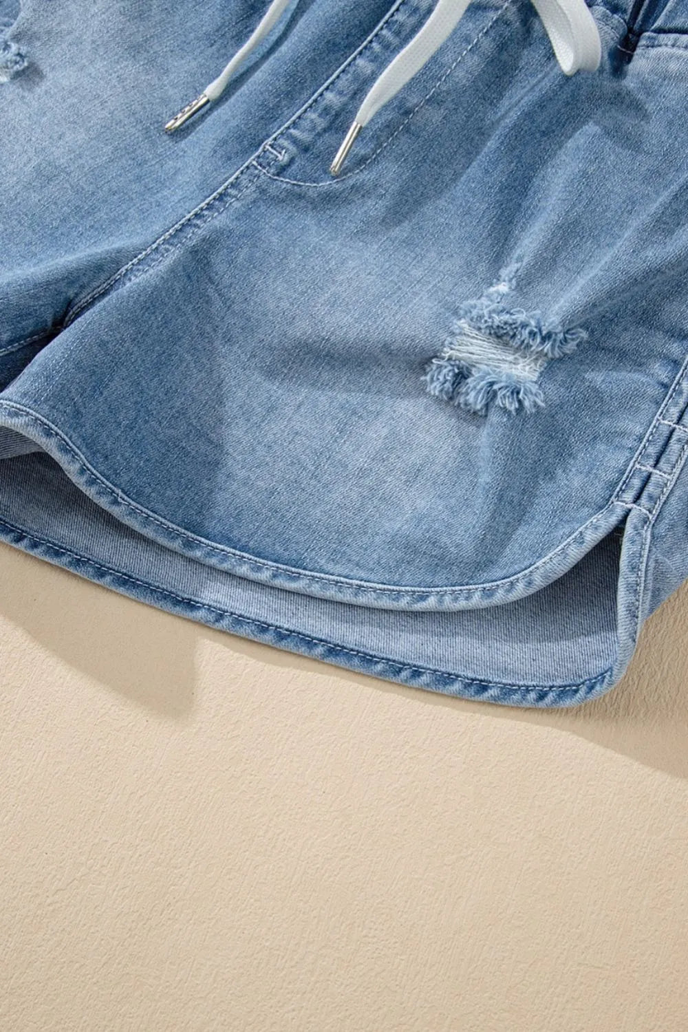 Medium-length distressed denim shorts with a drawstring waist from Trendsi, featuring high-rise fit and frayed hem details.