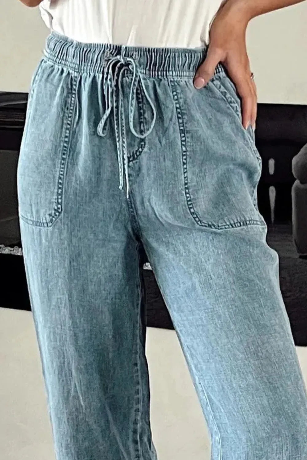 Medium-length drawstring high waist jeans with pockets by Trendsi, featuring a stylish fit and classic denim design.
