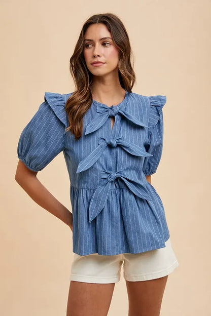 Denim peplum blouse by Annie Wear featuring a stripe front bow and stylish design, perfect for casual or chic outfits.
