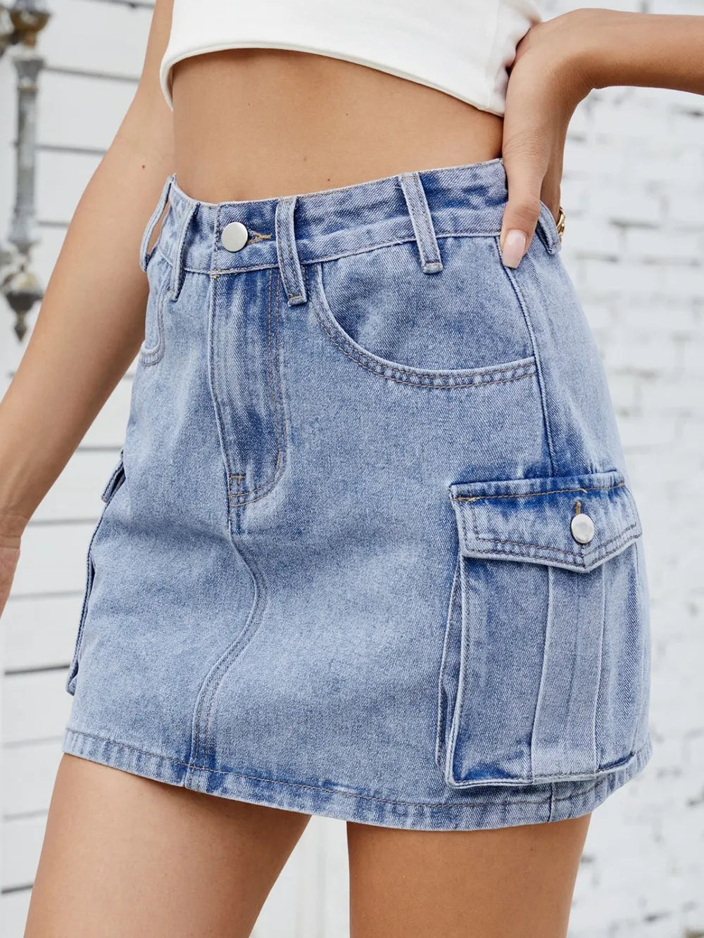 Medium-length denim cargo skirt by Trendsi featuring multiple pockets and a relaxed fit, styled with casual accessories.