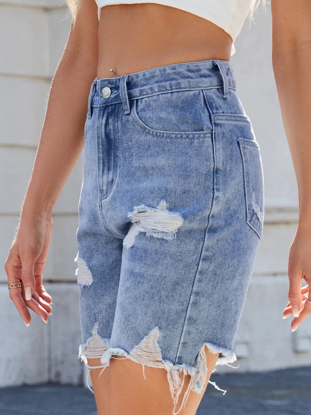 Light blue distressed raw hem denim shorts from Trendsi, featuring a casual fit and frayed edges, perfect for summer casual wear.