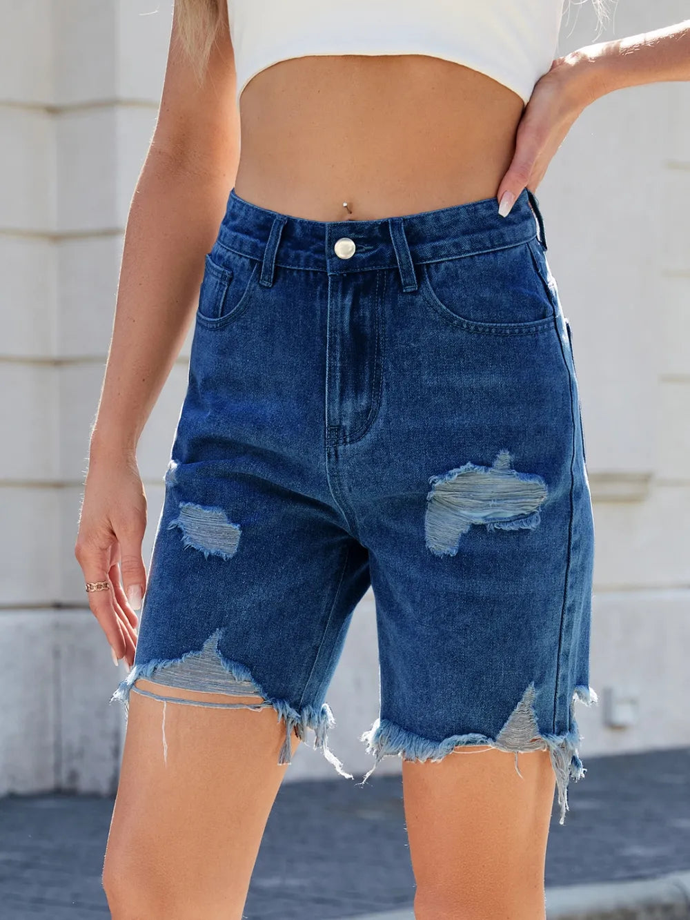 Distressed raw hem denim shorts by Trendsi featuring a casual fit, light wash, and frayed edges for a trendy summer look.