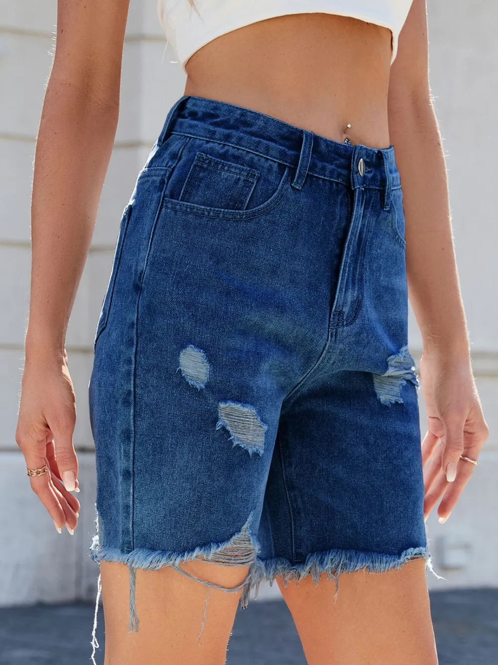 Medium wash distressed raw hem denim shorts by Trendsi, featuring frayed edges and casual fit, perfect for summer casual wear.