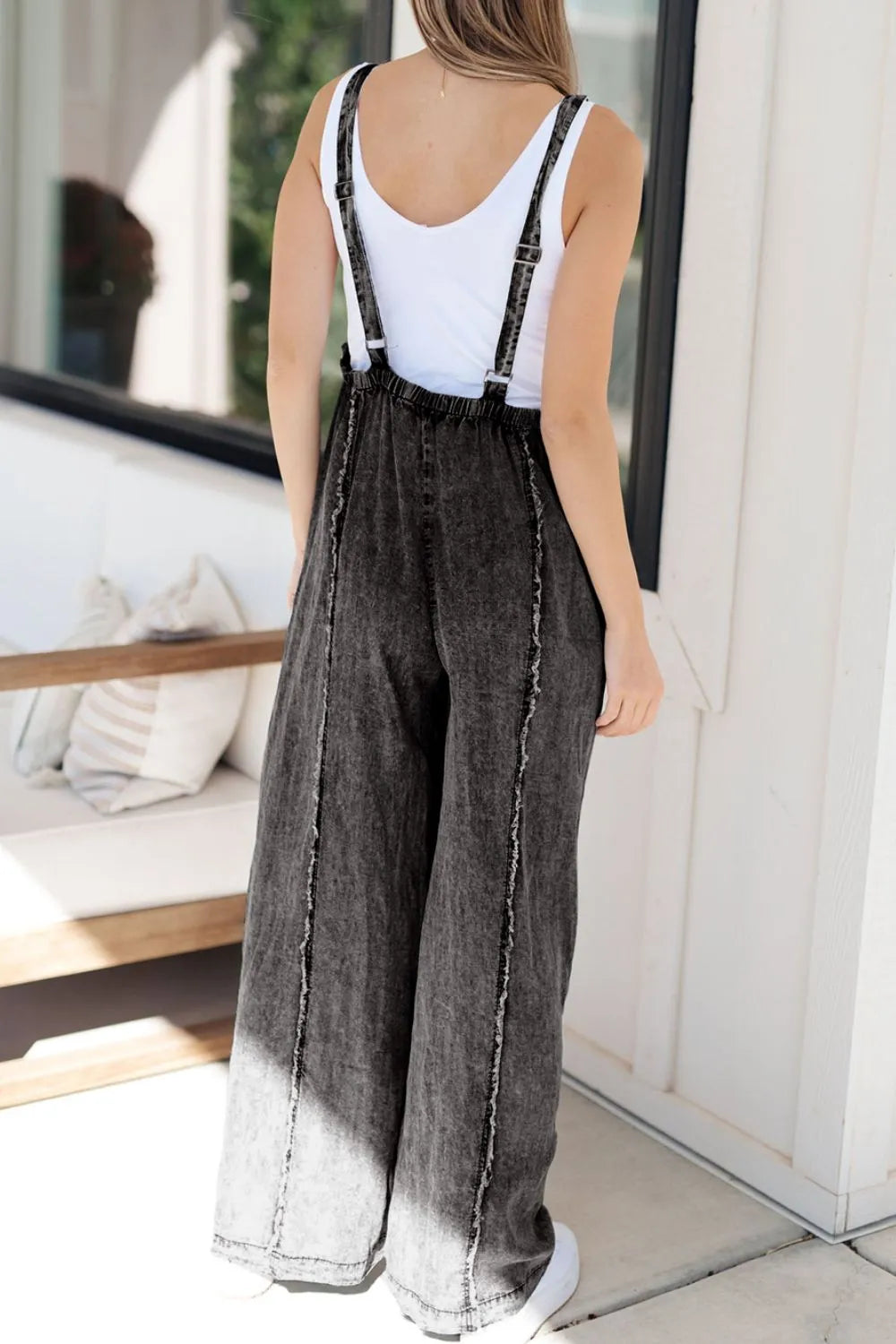 Light blue wide-leg denim overalls with frayed exposed seams and adjustable straps, styled by Trendsi.
