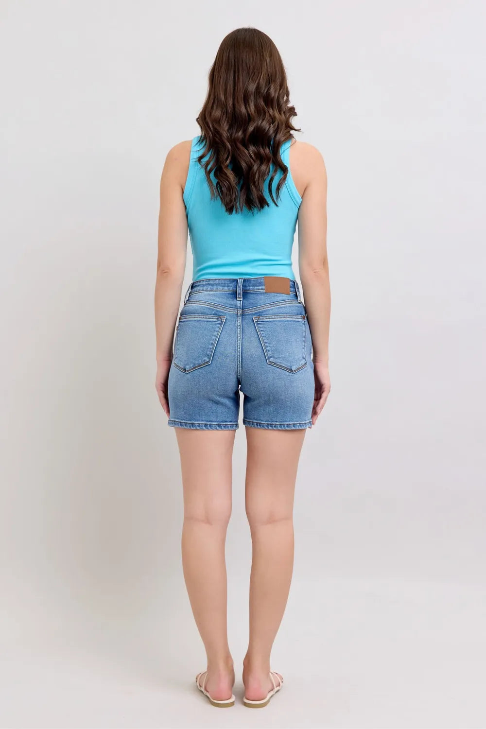 Plus size Judy Blue denim shorts with two-button front and pockets, featuring a medium wash and comfortable fit.