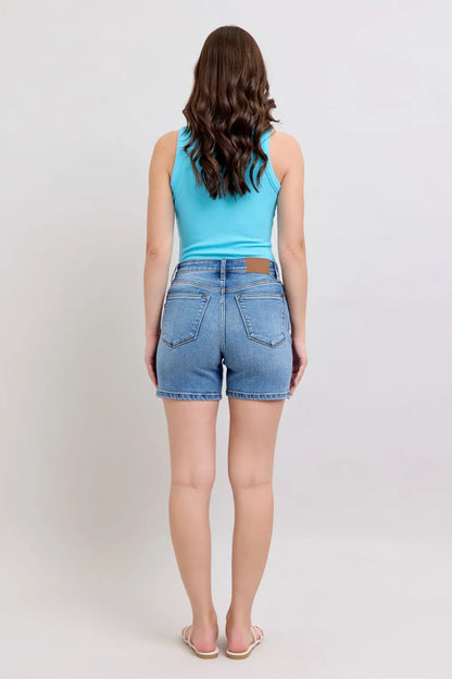Plus size Judy Blue denim shorts with two-button front and pockets, featuring a medium wash and comfortable fit.