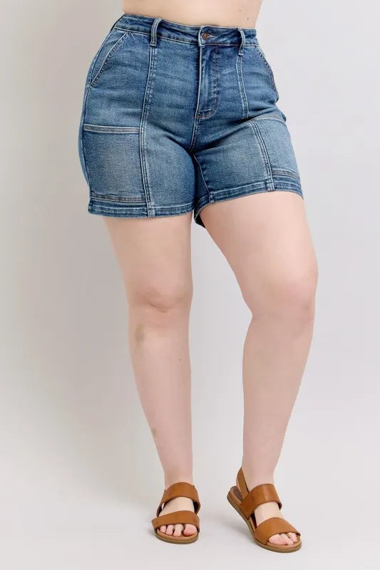 Plus size Judy Blue high rise denim shorts with a medium wash and classic five-pocket design, laid flat on a white background.