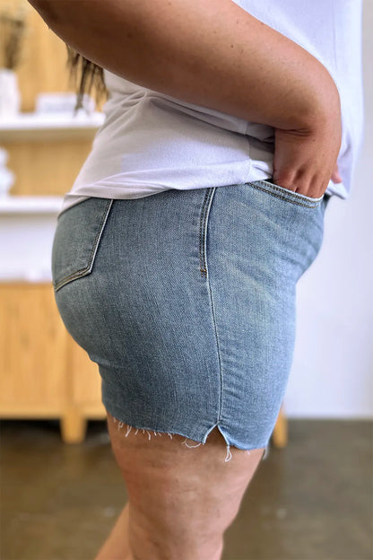 Judy Blue high waist raw hem denim shorts in medium wash, full size, showcasing distressed style and classic fit.