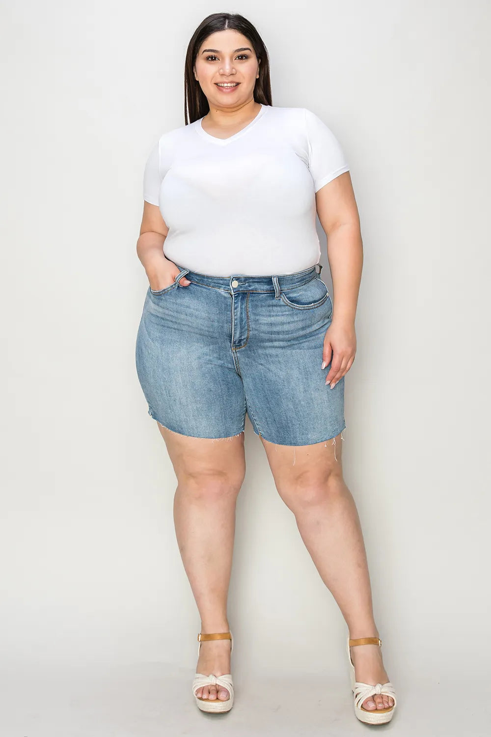 Full view of Judy Blue high waist raw hem denim shorts in medium wash, showcasing trendy distressed style and classic fit.