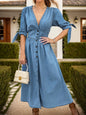 Medium-length denim dress by Trendsi featuring a plunge neckline, button-up front, and half-sleeves, styled for casual wear.