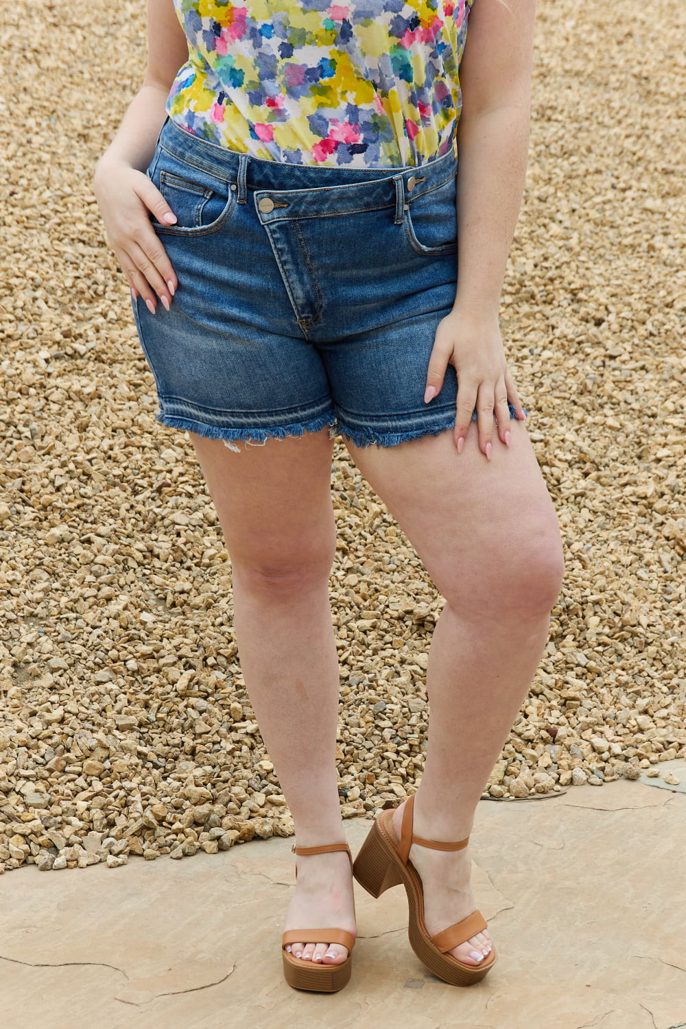 Trendsi RISEN Maya full-size mid-rise asymmetrical shorts displayed on a model, featuring a stylish cut and casual fit.