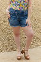 Trendsi RISEN Maya full-size mid-rise asymmetrical shorts displayed on a model, featuring a stylish cut and casual fit.