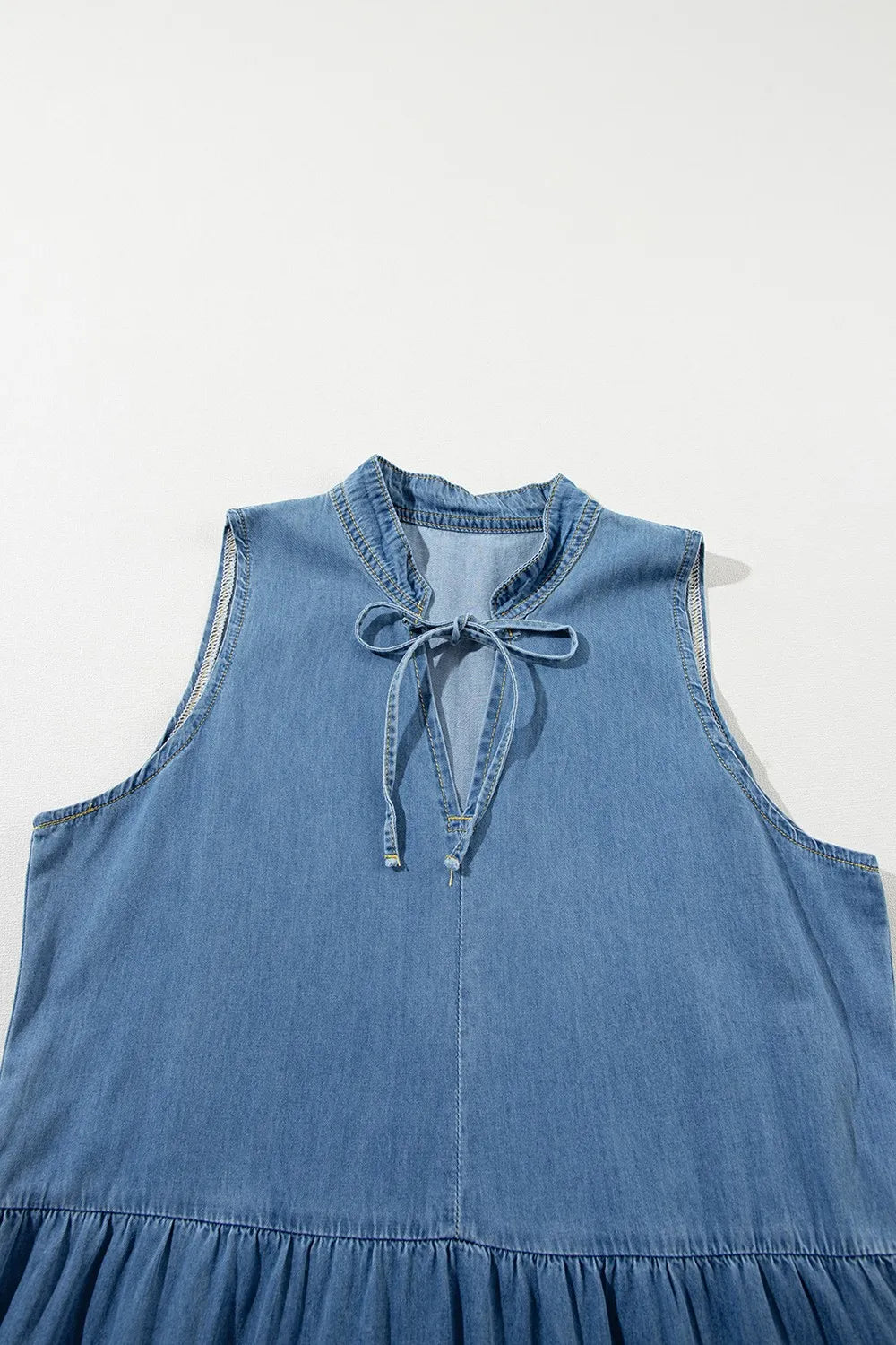 Medium-length denim maxi dress with a tie neck and tiered design from Trendsi, featuring long sleeves and a flowy silhouette.