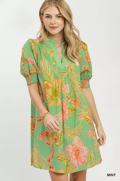 Mint green Umgee botanical print dress with smocked cuffs, featuring a flowy silhouette and vibrant floral pattern.