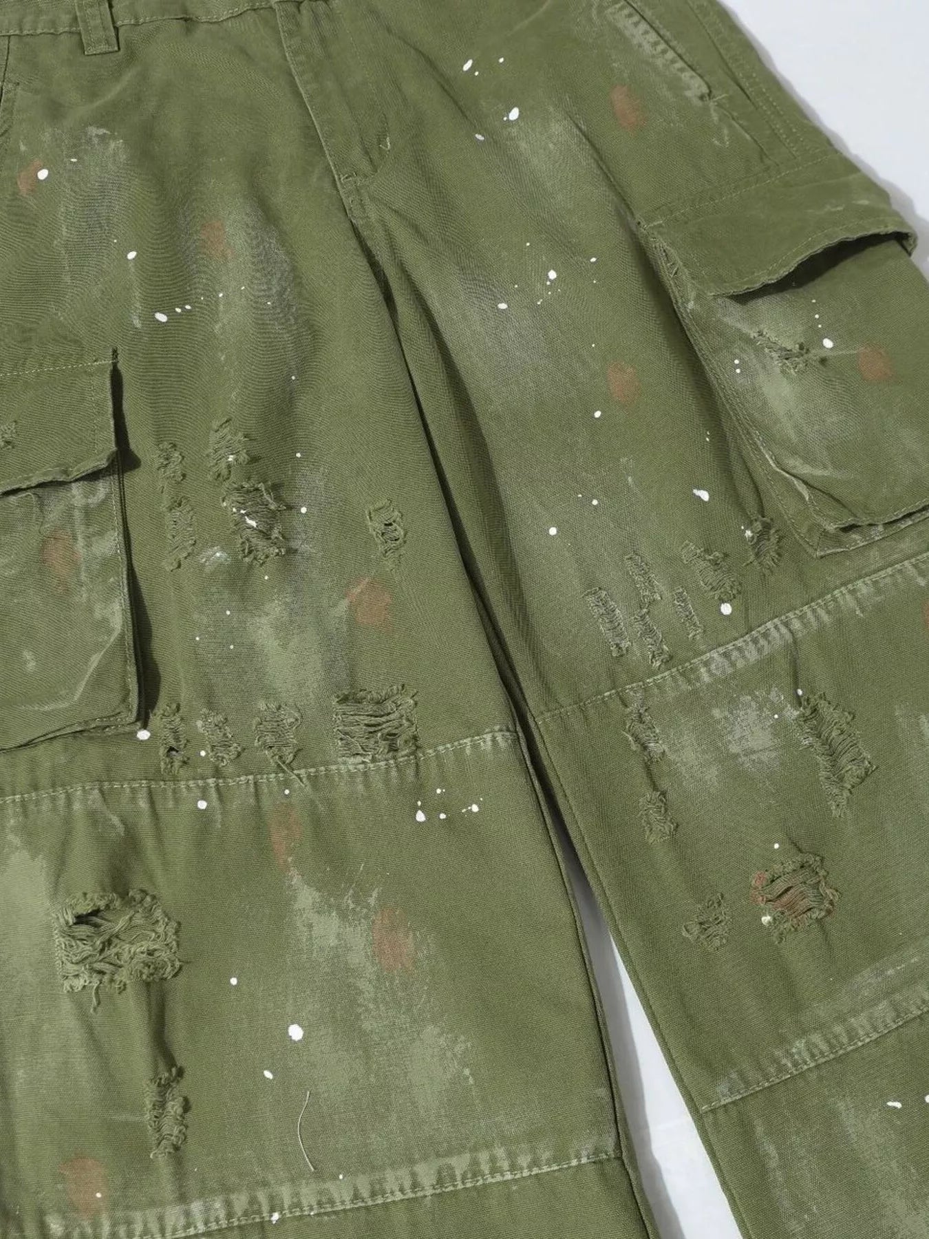 Men's distressed cargo pants with paint splatter from Trendsi, featuring multiple pockets and a rugged, casual style.