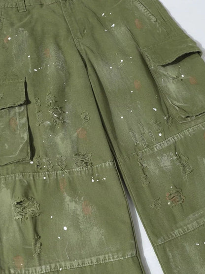 Men's distressed cargo pants with paint splatter from Trendsi, featuring multiple pockets and a rugged, casual style.