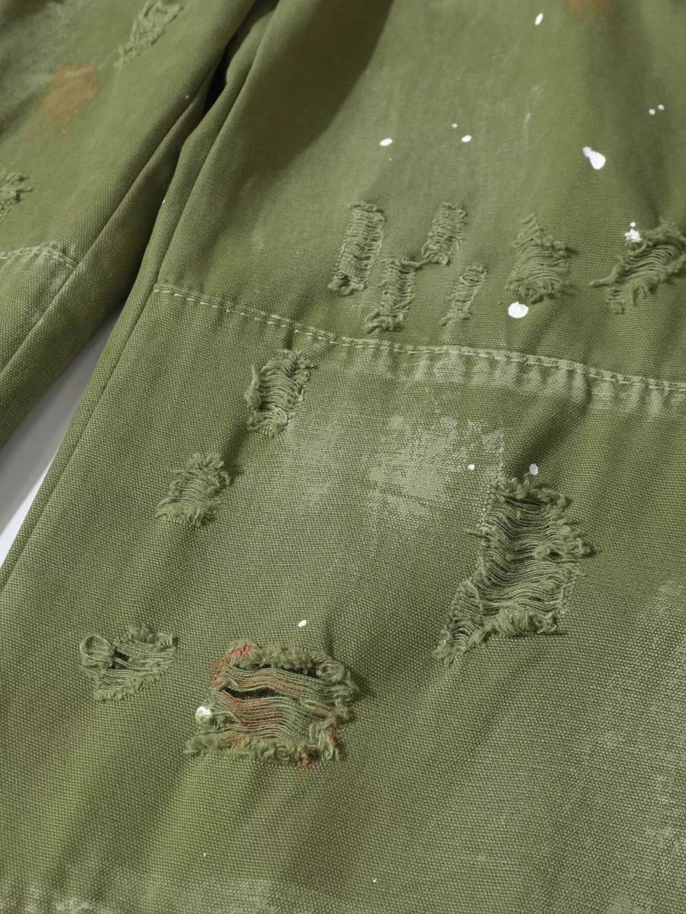 Men's distressed cargo pants with paint splatter from Trendsi, featuring a rugged design and multiple pockets.