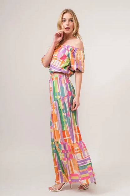 Asymmetric geo-printed tiered maxi skirt from Trendsi featuring vibrant geometric patterns and flowy fabric.