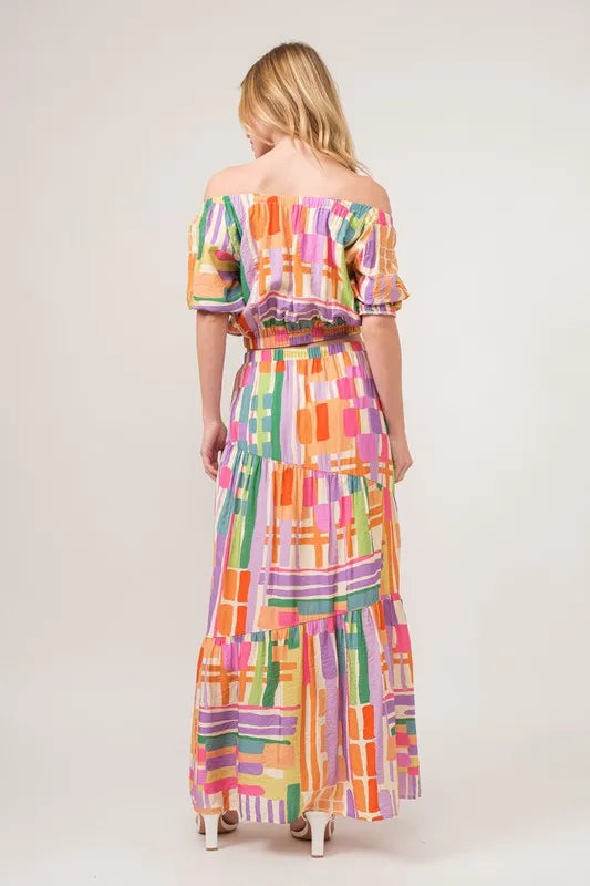 Asymmetric geo-printed tiered maxi skirt by Trendsi featuring bold geometric patterns and flowing fabric in vibrant colors.