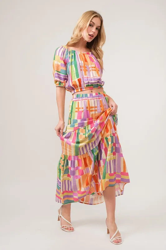 Trendsi Asymmetric Geo Printed Tiered Maxi Skirt featuring bold geometric patterns and flowing fabric for a stylish look.