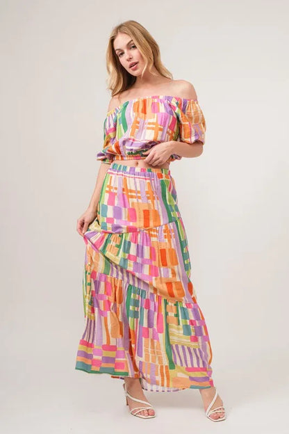Asymmetric geo printed tiered maxi skirt by Trendsi with colorful geometric patterns and flowing fabric.