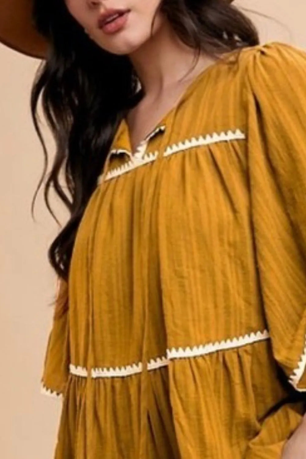 Mustard Annie Wear tiered dress with tassel contrast trim, tie neck, and half sleeves, featuring a stylish, feminine design.