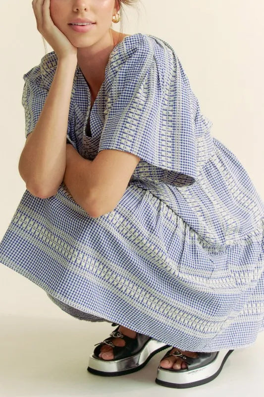 Navy blue Davi & Dani embroidered stripe ruffled gingham mini dress by Trendsi, featuring ruffled details and a classic gingham pattern.
