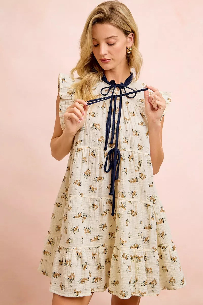 Oatmeal navy BiBi floral multi-tiered dress with ruffles and front tie, styled on a model with flowy fabric and feminine design.