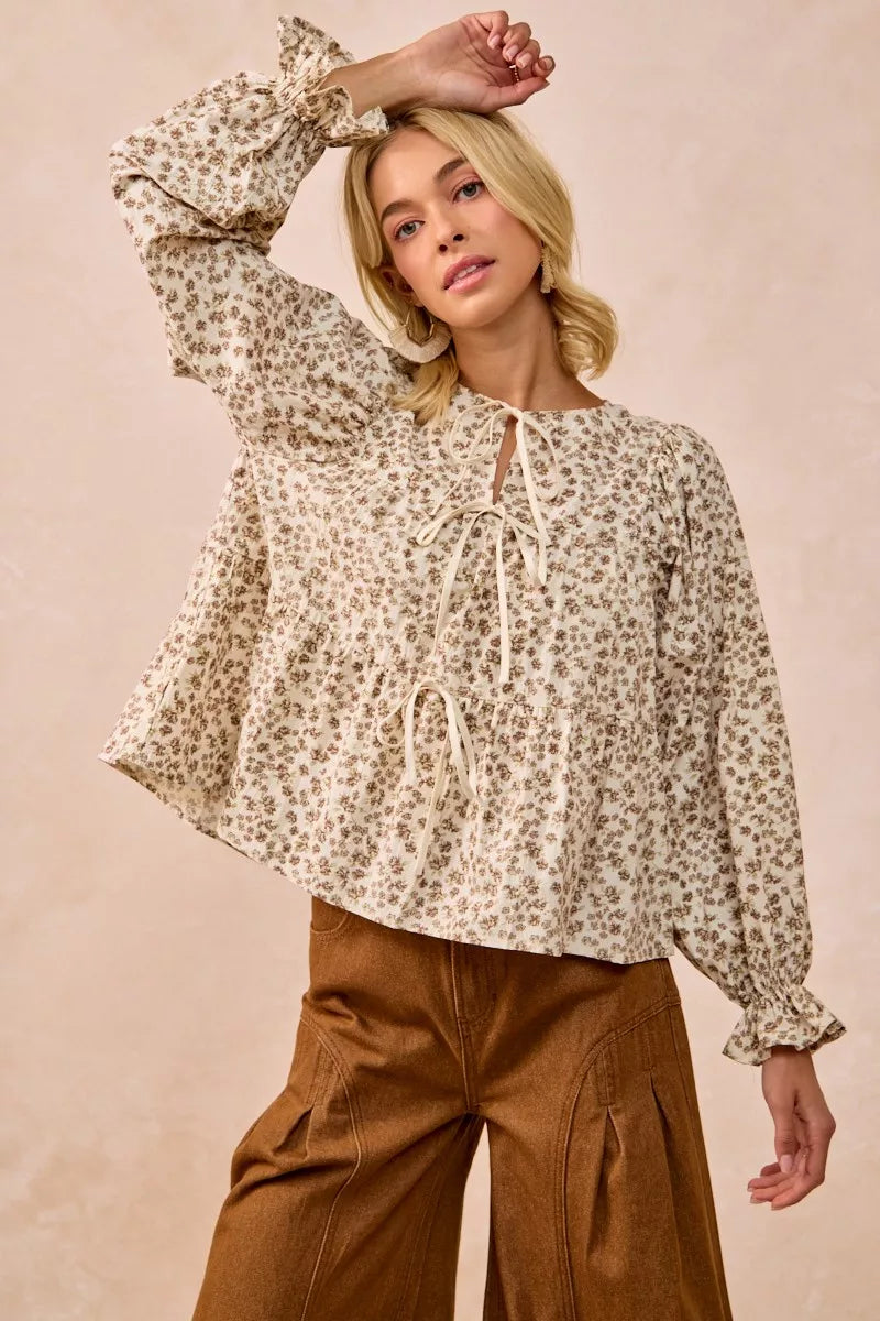 Oatmeal BiBi floral printed peplum blouse with shirring and tied details, styled with soft fabric and feminine design.