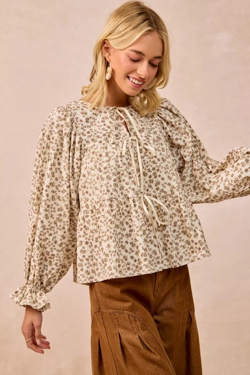 Oatmeal BiBi floral printed peplum blouse by Trendsi with shirring and tied detail, showcasing a feminine, flowy design.