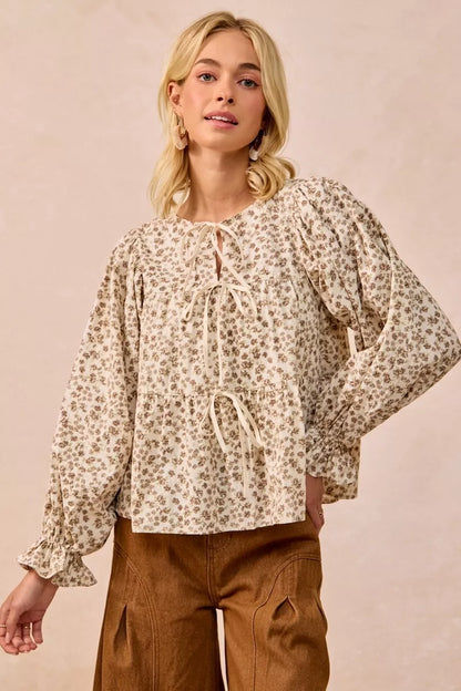 Oatmeal floral printed peplum blouse with shirring and tie details from Trendsi, featuring a feminine, ruffled design and lightweight fabric.