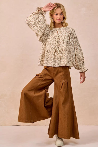 Oatmeal BiBi floral printed peplum blouse with shirring and tied details from Trendsi, shown on a hanger.