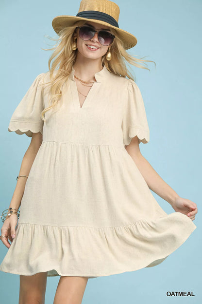 Oatmeal Umgee linen tiered babydoll dress with scalloped sleeve detailing, displayed on a hanger.