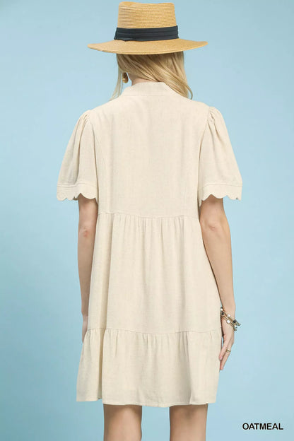 Umgee linen tiered babydoll dress with scalloped sleeves, in oatmeal, featuring a relaxed fit and feminine design.