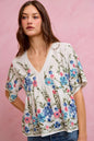 Off-white and blue floral embroidered baby doll blouse top by Trendsi, featuring delicate embroidery and a relaxed fit.