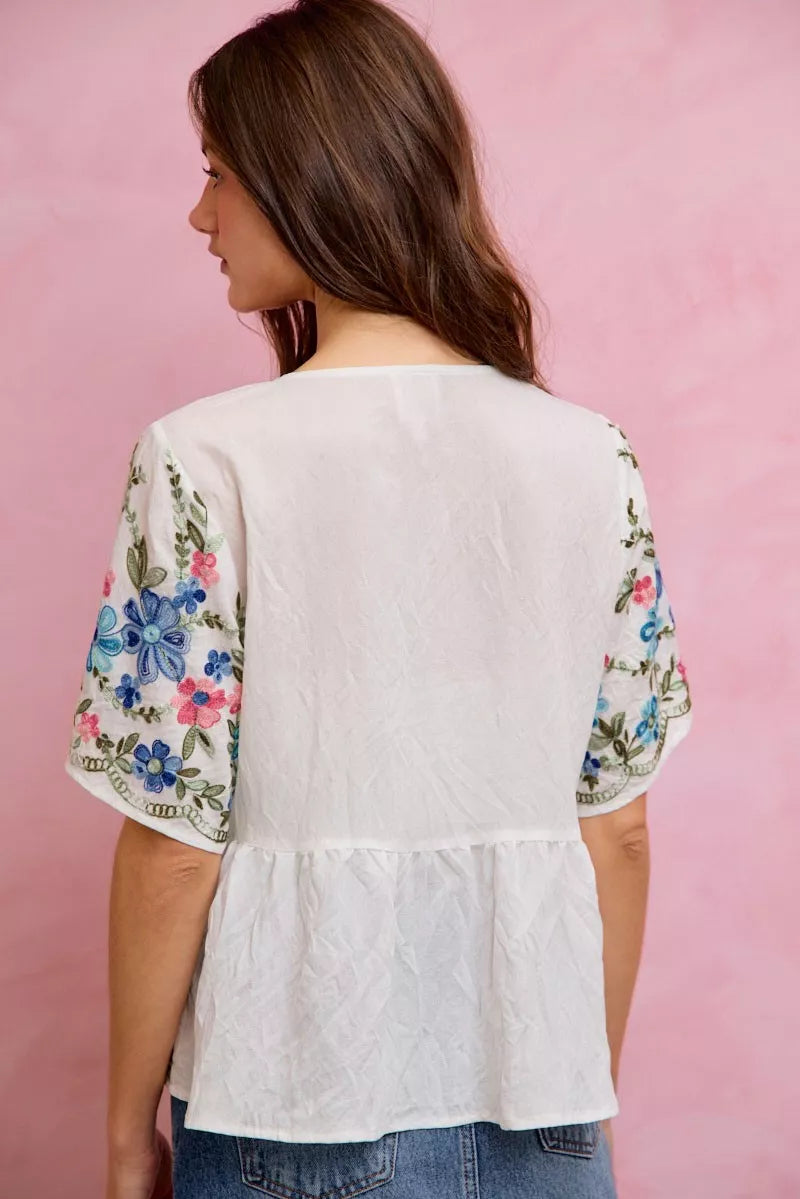 Off-white and blue floral embroidered baby doll blouse top by Trendsi, featuring delicate embroidery and a feminine fit.