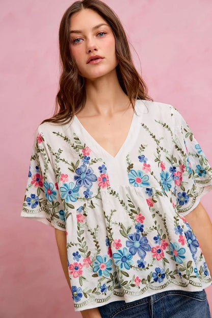 Off-white and blue floral embroidered baby doll blouse top by Trendsi, featuring delicate embroidery and a feminine fit.