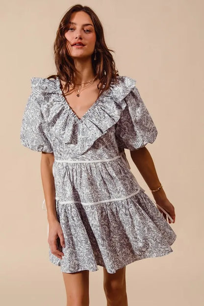 Off-white navy printed cotton dress with ruffle V-neckline and side tie from Trendsi, styled for casual and summer wear.